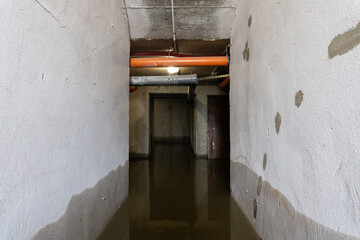 Interior fragment of a flooded basement. There are gray concrete walls and water on the floor....