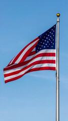 Fototapeta premium American flag waving against a clear blue sky stars and stripes white