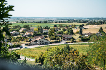 Scenic view of a rural French village surrounded by farmland and greenery under a clear sky. Return to the countryside, neo-ruralism, remote work migration, slow living