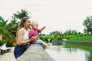 A loving mother and her energetic child delight in a joyful outing by the tranquil waterside,...