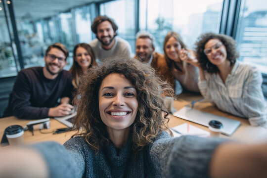 Happy young business team taking group selfie in modern office, capturing moments of teamwork and collaboration