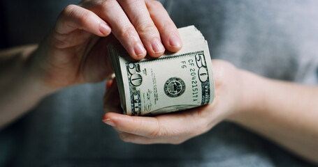 Hands, person and stack of dollars for fraud crime, money laundering and smuggling cash. Criminal,...