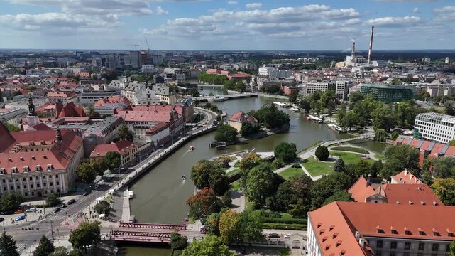 Drone video capturing panoramic aerial view of Wrocław, Oder River, bridges, urban architecture, green recreational areas, historic city center, Lower Silesia, Poland.