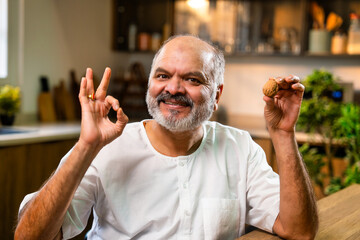 Elderly Indian man eats akhrot for health, nutrition, and wellness indoors
