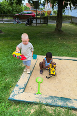 Children joyfully playing together in a sandbox, experiencing delightful moments filled with...