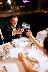 Couple toasting with champagne glasses at a romantic dinner celebration in an elegant setting