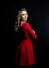 Elegant blonde woman posing in red dress on black background
