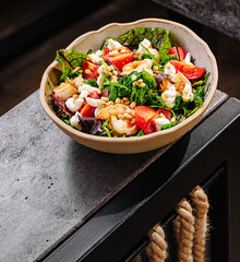 Fresh and colorful salad with greens, tomatoes, and nuts on a modern table