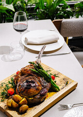 Elegant dining experience with grilled steak and wine in a lush setting