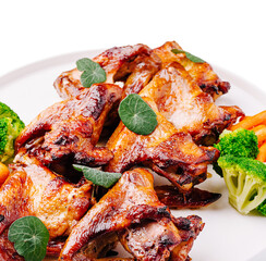 Grilled chicken wings garnished with herbs and fresh vegetables for a meal
