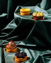 Colorful desserts arranged on a rich green fabric surface in a culinary display