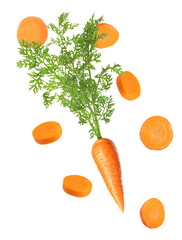 fresh carrots with green tops and sliced pieces arranged on black