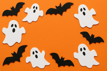 Fototapeta premium Halloween background with white ghost and black bat decoration on orange surface creating festive and spooky atmosphere perfect for seasonal celebration or party invitation