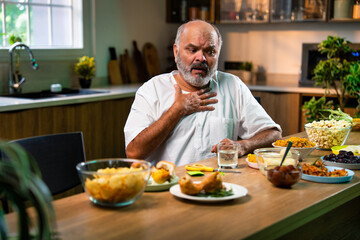 Elderly Indian man drinks antacid in modern kitchen after eating