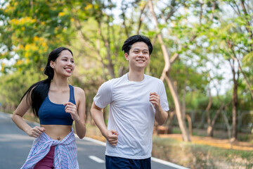 Asian young couple doing running exercise in the morning outdoors garden.