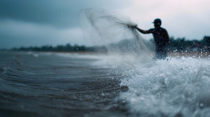 Silhouette of a fisherman casting a traditional net into the choppy sea with water splashing under a vast moody sky