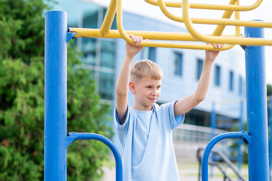 Teen boy training on monkey bars in summer park