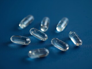 Transparent Gel Capsules on Dark Blue Surface, Pharmaceutical Product Close Up.