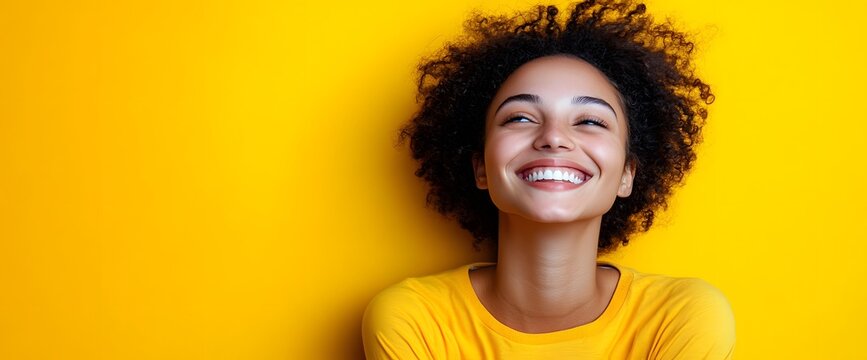 A young woman is joyfully smiling while leaning against a bright yellow wall - Powered by Adobe