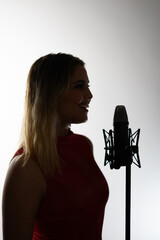 Female singer performing with microphone in recording studio silhouette