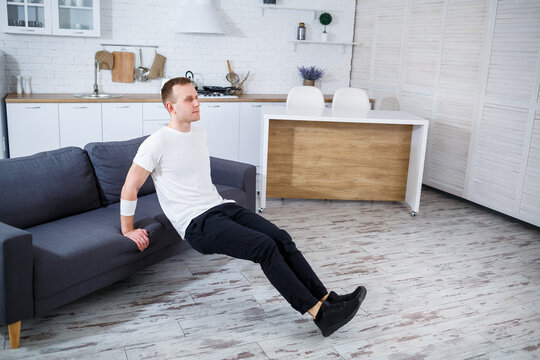 Home Workout Routine A Young Man Engaging in Tricep Dips Using His Sofa for an Effective Strength Training Session in a Stylish and Modern Living Room Environment with Comfortable Decor