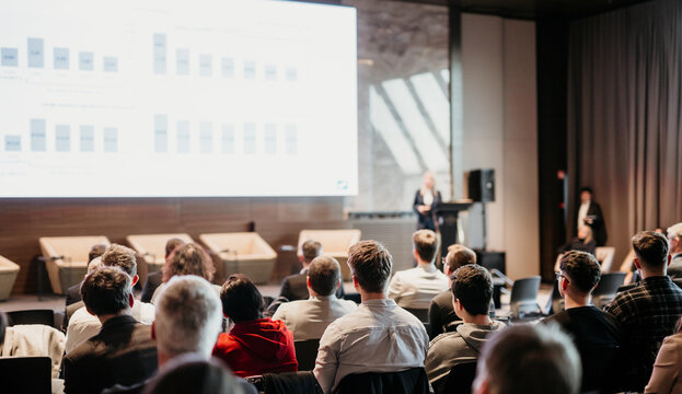 Female speaker giving a talk on corporate business conference. Unrecognizable people in audience at conference hall. Business and Entrepreneurship event
