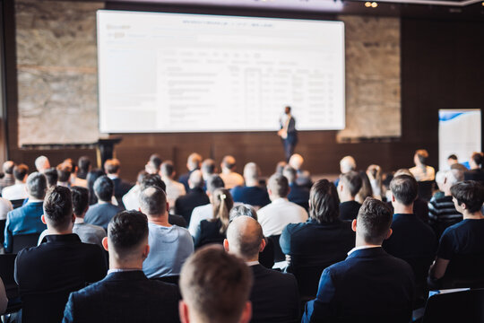 Speaker giving a talk in conference hall at business event. Rear view of unrecognizable people in audience at the conference hall. Business and entrepreneurship concept