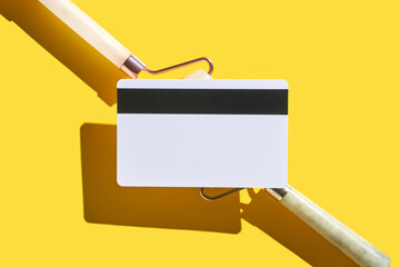 Blank white card with black magnetic stripe on yellow background with shadows.