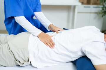 Fototapeta premium Nurse provides back massage to senior patient in clinic. Perfect for physiotherapy, rehabilitation, aging care, wellness, pain relief, and professional healthcare themes.