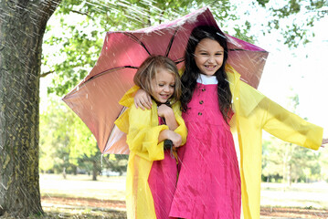 Happy girls, sisters are laughing and playing in the rain. Children enjoy a summer day