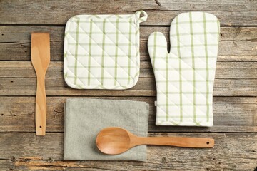 Oven glove and other kitchen utensils on wooden table, flat lay