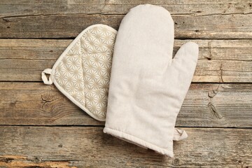 Oven glove and potholder on wooden table, top view