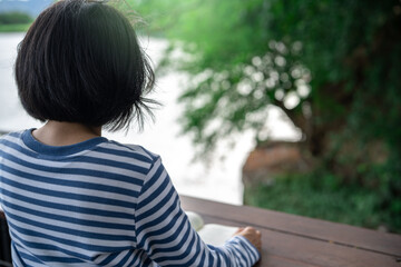 Rearview of a woman sitting on a balcony reading a book, representing a digital detox retreat,...