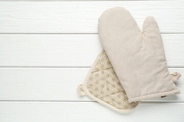 Oven glove and potholder on white wooden table, top view. Space for text