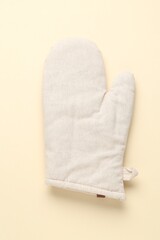 One oven glove on beige background, top view