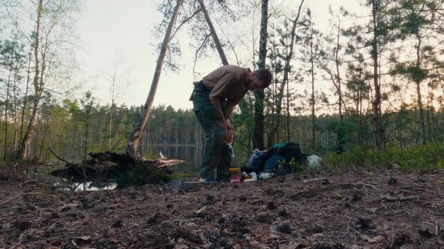 Tourist Filtering Water from Lake for Drinking at Sunset in the Forest