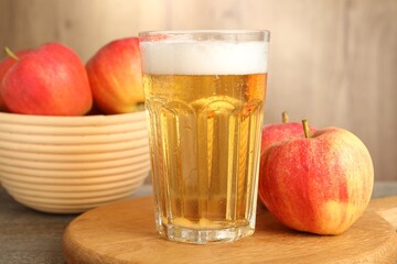 Delicious cider in glass and apples on wooden table, closeup