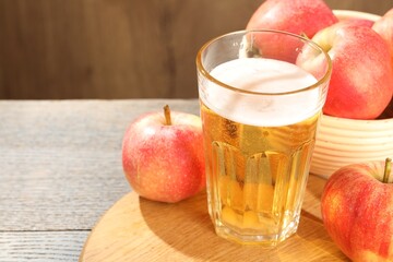Delicious cider in glass and apples on wooden table, closeup