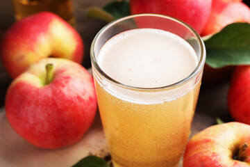 Delicious cider in glass and apples on table, closeup