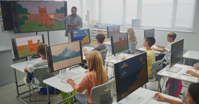 Elementary School Children Using Computers, Creating Digital Illustrations. African American Teacher Teaching Young Boys and Girls During Art Lesson Using Digital Screen. STEM Education. Static Shot.