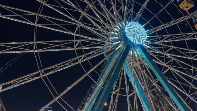 Dazzling Ferris wheel illuminated with bright lights against a dark night sky, a thrilling ride experience