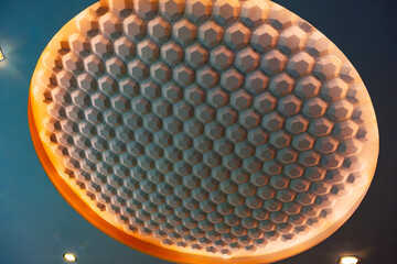 a modern architectural ceiling featuring a grid of rectangular panels. Small, evenly spaced recessed lights are embedded in the ceiling, casting a soft, diffused glow.