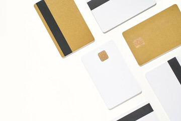 Arrangement of gold and white credit cards with chips and magnetic stripes on white background.