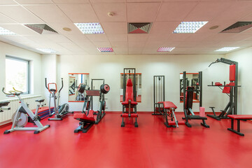 Interior of a modern hotel gym with exercise equipment and  red floor