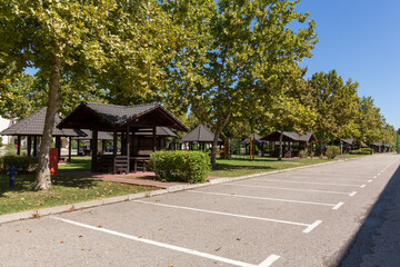 Wooden gazebos in green park area with empty parking lot