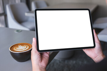 Mockup image of a woman holding digital tablet with blank white desktop screen in cafe