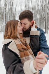 In a picturesque snowcovered forest, a couple finds warmth in each others arms, sharing a tender moment filled with affection and joy, surrounded by the serene beauty of nature and snowflakes