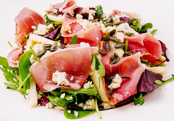 Fresh salad with prosciutto and mixed greens topped with seeds