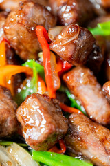 Close-up of glazed meat with bell peppers and green onions in a savory sauce. Colorful stir-fry...
