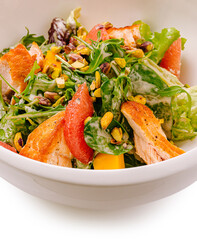 Fresh mixed salad with grilled chicken and roasted pistachios served in a bowl